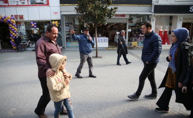 Başında fötr şapka elinde mikrofon seçim çalışması yürütüyor